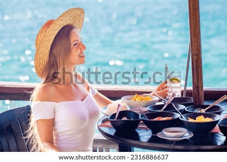 A young woman on summer vacation enjoys a delicious breakfast in a luxury hotel resort with a sea view. Girl enjoying her summer vacation.