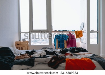 Cluttered and untidy apartment bed room full of colorful clothes on everywhere. Royalty-Free Stock Photo #2316889383