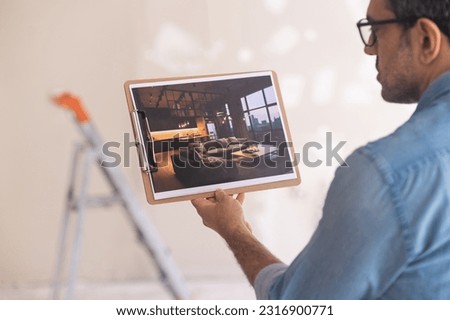 Man imagining finished renovation in new house looking at picture with interior design in modern loft style home owner ready for renovation process in living room