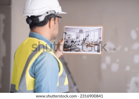 Specialist in white helmet looks at picture with contemporary interior design in Scandinavian style worker in professional uniform imagining result of renovation in apartment