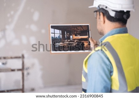 Engineer in protective helmet holding picture with stylish loft interior in hand stands in room in process of renovation worker in professional uniform imagining ultimate apartment interior