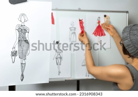 The tailor designs the dresses. The fashion designer develops sketches of women's fashionable clothes. Seamstress workplace. Royalty-Free Stock Photo #2316908343