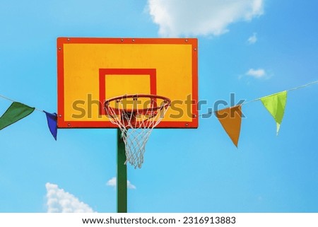 Bright yellow and red colored basketball backboard against blue sky outdoor. Basket metal hoop for basketball game competition at city street. Royalty-Free Stock Photo #2316913883