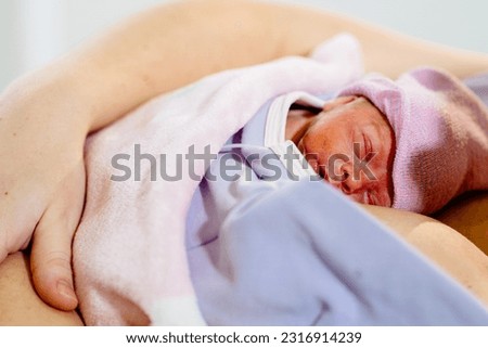 Freshly premature baby born skin to skin on unrecognizable mothers chest caucasian female newborn first breath of life Kangaroo care with skin to skin contacthealthy relieved mother baby. 