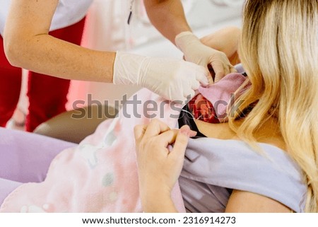 Mom hugs and holds in her arms a premature prematurely born girl in intensive care for a newborn. Skin to skin contact. Medical worker help. Kangaroo care concept. Royalty-Free Stock Photo #2316914273