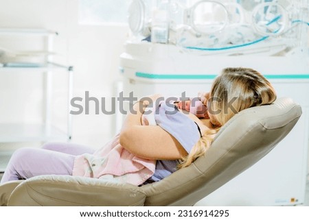 Mom hugs and holds in her arms a premature prematurely born girl in intensive care for a newborn. Kangaroo care concept.