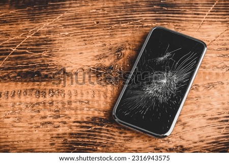 Smartphone with cracked screen over wooden background