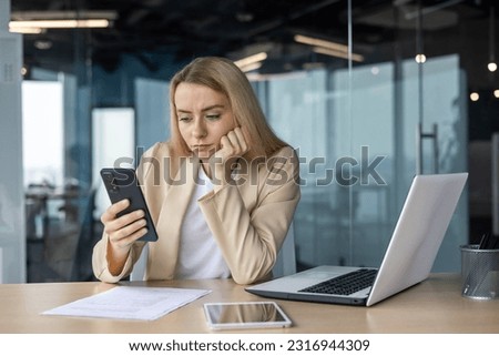Sad and disappointed woman received bad news online, business woman at workplace inside office in depression reading bad news using app on smartphone, female worker with phone in hands thoughtful. Royalty-Free Stock Photo #2316944309