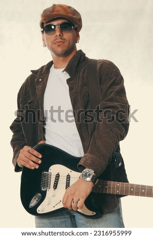 
Young stylish guitarist in jacket and hat. Blues and rock