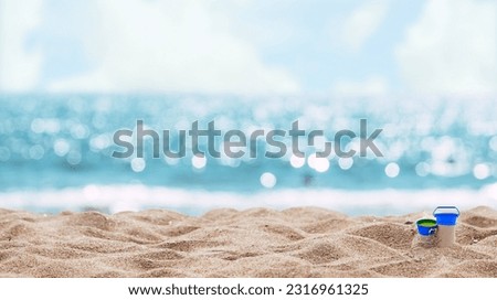 An abstract seascape beach background with a soft blur of bokeh light illuminating the calm sea and sky, while the focus lies on the sandy foreground.