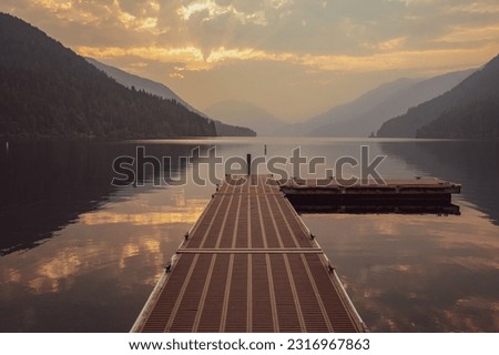 Looking out over pier at Lake Crescent and mountains with morning sunlight shining through clouds | Olympic National Park, Washington, USA Royalty-Free Stock Photo #2316967863