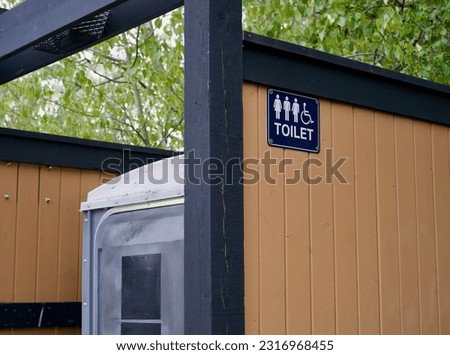 Outdoor porta potty toilet with an all genders and handicapped accessible sign 
