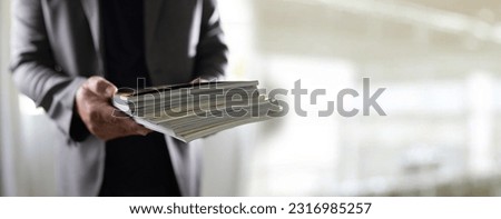 man holding a magazine publication page media stack to stack communication research data to learn advertising and banner space objects Royalty-Free Stock Photo #2316985257