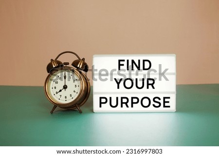 Find Your Purpose text message on paper card with wooden easel and alarm clock