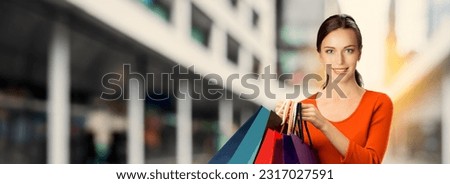 Photo image concept - beautiful woman wear orange red dress hold, show many shop bags, stand against blurred mall building background. Sale discounts offers rebates, consumer bank credit ad. Cash back