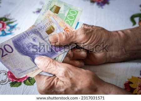 A Swedish pensioner holds a bunch of low denomination banknotes in her hands, Cost of living for a senior in Sweden, Pensions and the Swedish social system for the elderly, financial concept Royalty-Free Stock Photo #2317031571