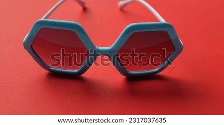 close up blue pentagon shape sunglasses isolate on a red background
