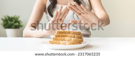 Gluten allergy, asian young woman hand push out, refusing to eat white bread slice on plate in breakfast food meal at home, girl having a stomach ache. Gluten intolerant and Gluten free diet concept. Royalty-Free Stock Photo #2317065235