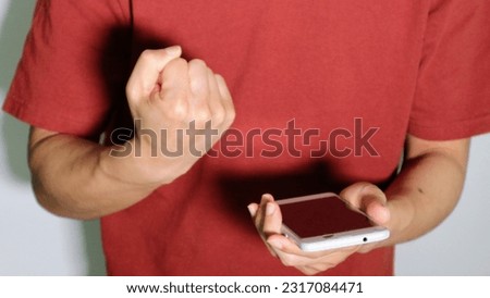 A person holding a smartphone and doing a guts pose