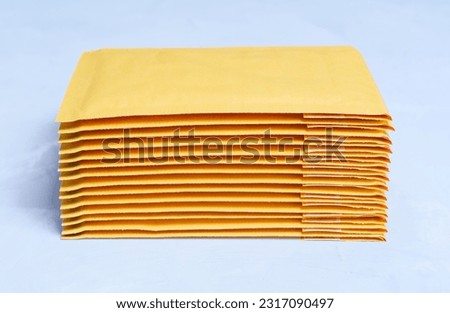 Close-up of yellow padded envelopes stacked on a grey concrete background. Royalty-Free Stock Photo #2317090497