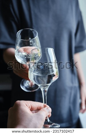 A glass of white wine in the hands of a girl. Tasting of alcoholic beverages. Summer rest. Romantic evening aperitif. Close-up of a glass of wine. Enjoy the moment