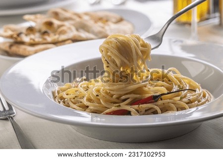 Spaghetti aglio e olio spinned on a fork taking a mouthful portion of pasta out of the plate. Royalty-Free Stock Photo #2317102953