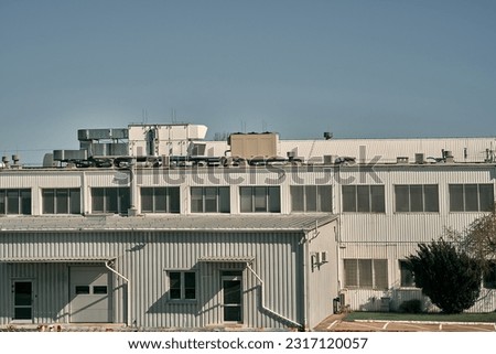 modern industrial warehouse exterior. The warehouse is a large, purpose-built building designed for industrial purposes.  Its architecture features a clean and contemporary design. Royalty-Free Stock Photo #2317120057