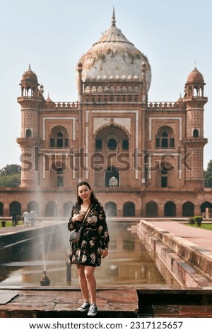 Attractive east asian woman in dress stands in front of tomb of Safdar Jang in New Delhi, India, tattooed young girl full body portrait in indian touristic spot, woman tourist in India Royalty-Free Stock Photo #2317125657