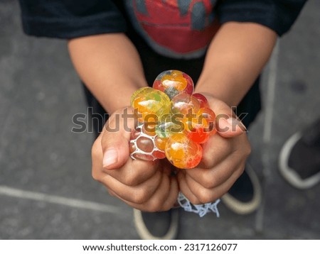 A kid holding and squeezing  a colorful stress relief grape balls Royalty-Free Stock Photo #2317126077