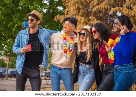 Group portrait of multi ethnic friends having a party in a park - Diverse young people with glasses of beer at a summer party - Happy hour, lunch break and youth concept