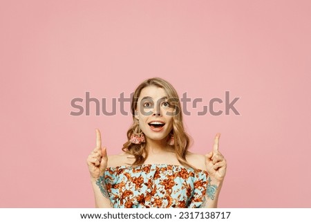 Young blonde woman wears summer casual clothes point index finger overhead indicate on workspace copy space mock up isolated on plain pastel light pink background studio portrait. Lifestyle concept