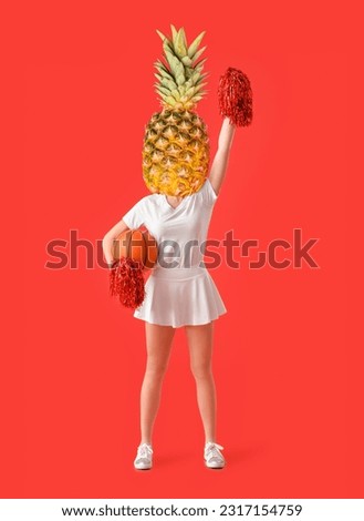 Beautiful cheerleader with ball for playing basketball and ripe pineapple instead of her head on red background