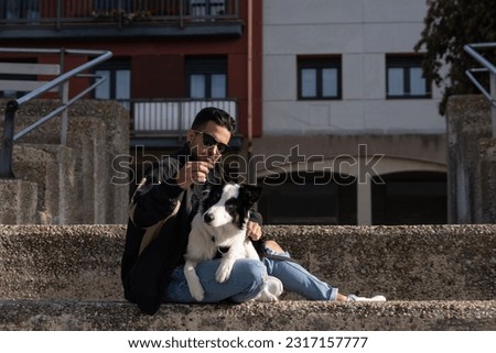 A young Border Collie dog is lying on his owner's lap in the street with his young master. Pictures of pet Border Collie dogs with their owners.