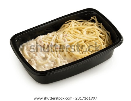 Pasta carbonara in a black plastic tray on a white background, isolated with clipping path. Royalty-Free Stock Photo #2317161997