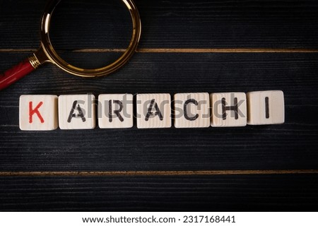 KARACHI. Word from alphabet blocks and magnifying glass on wood texture background.