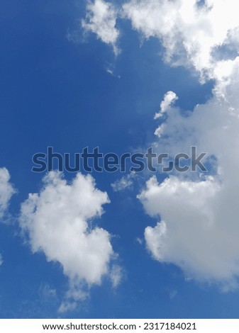 Beautiful white clouds on deep blue sky background. Large bright soft fluffy clouds are cover the entire blue sky.