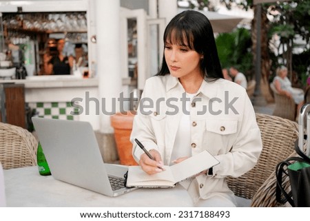 Beautiful happy woman works with a laptop in a coffee shop