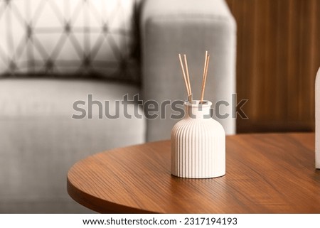 Bottle of reed diffuser on table in room, closeup Royalty-Free Stock Photo #2317194193