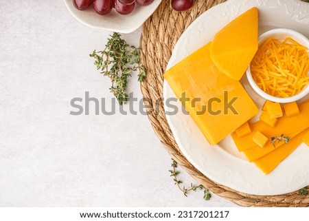 Plate with tasty cheddar cheese and grapes on light background Royalty-Free Stock Photo #2317201217