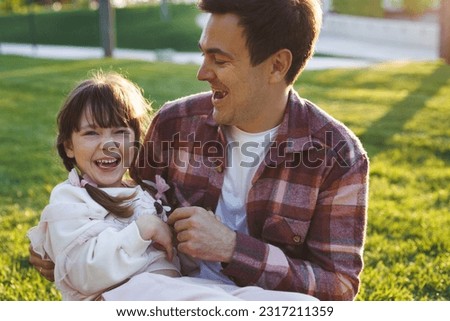 Happy father hugs his little daughter. The family is laughing and having fun at sunset