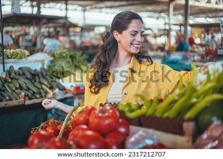 Beautiful young woman buying vegetables. Young cheerful woman at the market. Raw food, veggie concept. Portrait of smiling good looking girl in casual clothing Royalty-Free Stock Photo #2317212707