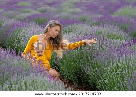 Mother with her baby sitting down in the lavender plantation enjoying the color and the very strong smell