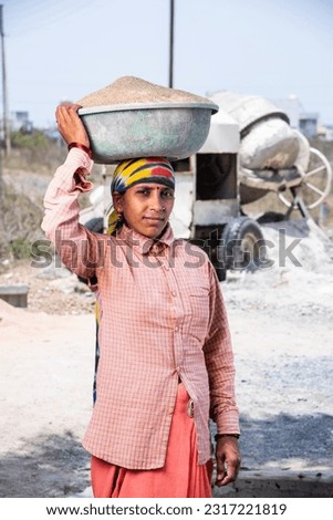 Asian Indian woman labour or worker working at construction site Carrying sand on her head. Royalty-Free Stock Photo #2317221819