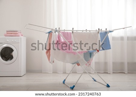 Clean laundry hanging on drying rack indoors Royalty-Free Stock Photo #2317240763