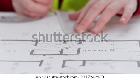 Schoolgirl imitates role of architect and makes line on flat layout with ruler. Little girl draws circle with protractor and pencils on drawing of apartment closeup