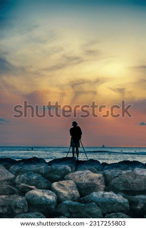 Photographer taking pictures of the sunset over the ocean near Honoluu, Hawaii.