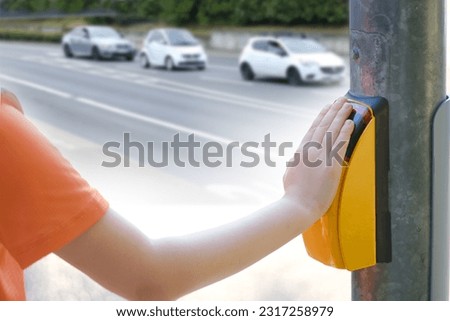child, boy 9-10 years presses yellow button pedestrian crossing to turn on green light traffic light to cross street of city, concept of primary school student, blurred street, urban landscape