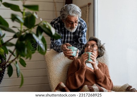 A sweet conversation between an elderly husband and wife over a cup of fragrant tea. Husband and wife of mature age look gently at each other in a cozy room