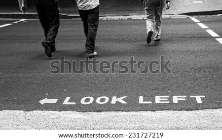 Street photography, sign look left with people going through the street, B&W photo, street, people in the street, street sign, be careful
