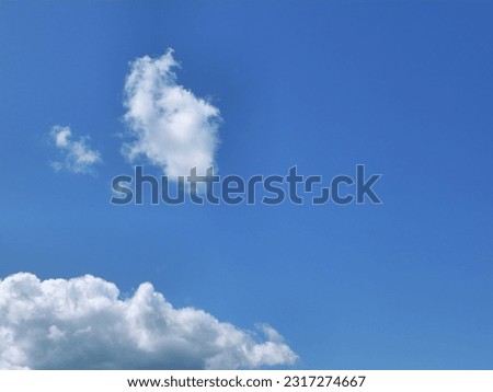 The sky is adorned with pristine white clouds floating against  backdrop of vibrant blue. These fluffy, cotton-like clouds create serene and peaceful atmosphere, enhancing  beauty of natural world.